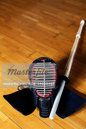 Female Japanese Kendo fighter kneeling on wooden floor, fastening