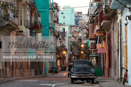 Street scene before sunrise showing dilapidated buildings crowded together and vintage American cars, Havana Centro, Havana, Cuba, West Indies, Caribbean, Central America