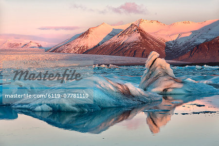 View across the calm water of Jokulsarlon glacial lagoon towards snow-capped mountains and icebergs bathed in winter morning light, at the head of the Breidamerkurjokull Glacier on the edge of the Vatnajokull National Park, South Iceland, Iceland, Polar Regions View across the calm water of Jokulsarlon glacial lagoon towards snow-capped mountains and icebergs bathed in winter morning light, at the head of the Breidamerkurjokull Glacier on the edge of the Vatnajokull National Park, South Iceland, Iceland, Polar Regions