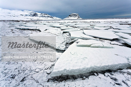 Winter view over slabs of broken lake ice covered in snow towards Kirkjufell (Church Mountain), near Grundarfjordur, Snaefellsnes Peninsula, Iceland, Polar Regions