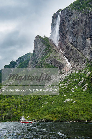 Little tourist boat under the Pissing Mare Falls in the western Brook Pond, Gros Morne National Park, UNESCO World Heritage Site, Newfoundland, Canada, North America