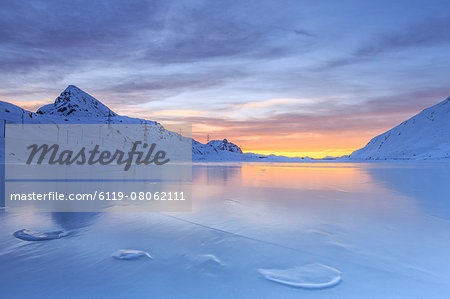 The colors of dawn invading the smooth surface of Lago Bianco exceptionally icy, Bernina Pass, Graubunden, Swiss Alps, Switzerland, Europe