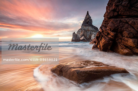The fiery sky at sunset is reflected on the ocean waves and cliffs, Praia da Ursa, Cabo da Roca, Colares, Sintra, Portugal, Europe