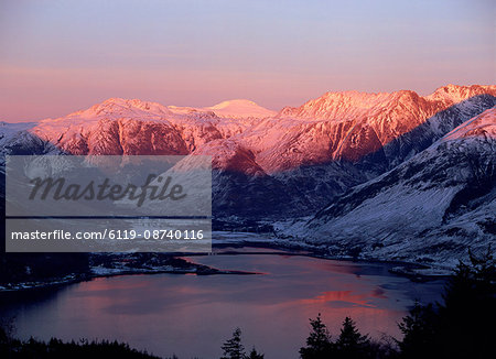 Mountains and Loch Duich head at dusk, with pink light on the snow reflected in water of the lake, from Bealach Ratagain viewpoint, Ratagain Pass, Highlands, Scotland, United Kingdom, Europe
