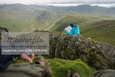 A woman checks her map while looking towards Great Langdale valley from the Langdale Pikes, Lake District National Park, Cumbria, England, United Kingdom, Europe