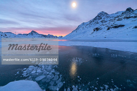 Ice bubbles frame the frozen Lago Bianco at dawn, Bernina Pass, canton of Graubunden, Engadine, Switzerland, Europe