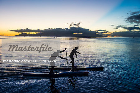 Stand up paddlers working out at sunset with Moorea in the background, Papeete, Tahiti, Society Islands, French Polynesia, Pacific