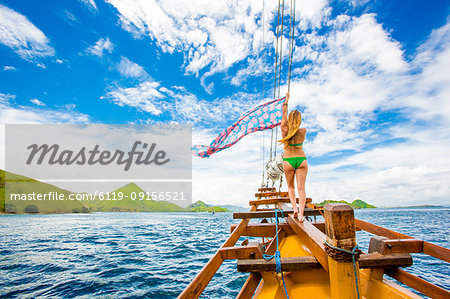Girl perched on bow of Phinisi Boat, sailing through Komodo National Park, Indonesia, Southeast Asia, Asia