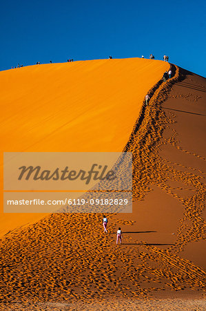 Visitors climb massive orange sand dune known as Dune 45, Sossusvlei area, Namib Desert, Namib-Naukluft, Namibia, Africa