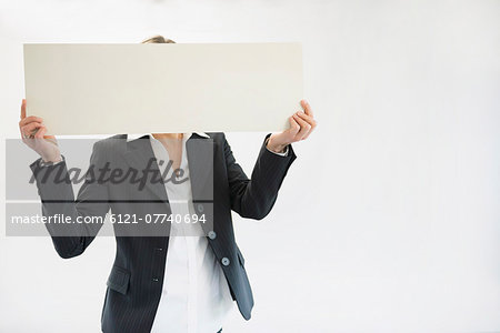 Businesswoman in black suit holding blank placard Businesswoman in black suit holding blank placard