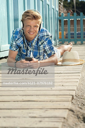 Teenager lying on front beach listening music Teenager lying on front beach listening music