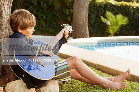 Boy playing guitar by pool