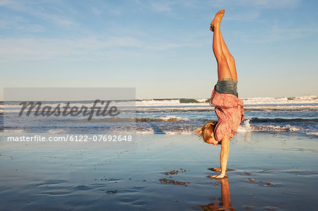 Girl doing handstand on the beach