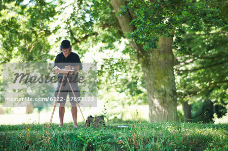 Man painting a picture in a park