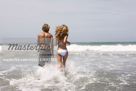 Guy and girl running in water on beach