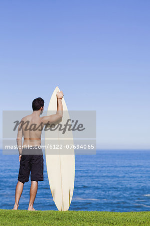 Man holding surfboard by ocean