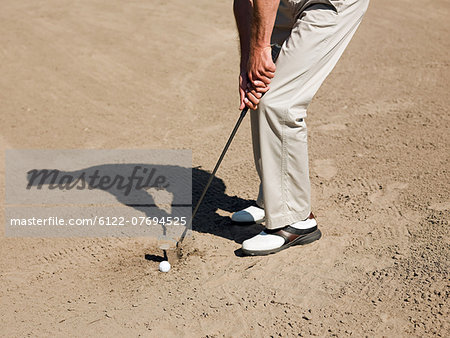 Man playing golf, stuck in bunker