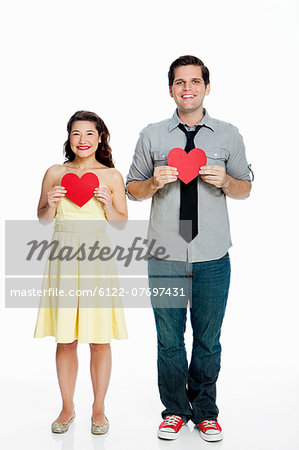 Young couple holding heart shapes against white background