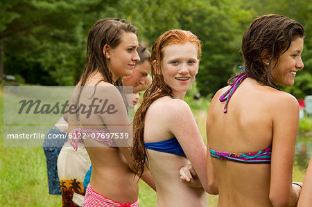 Girls in bikinis watching friends playing around in the country