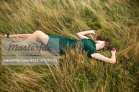 Young woman lying down in a field in a green dress