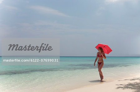 Woman walking with umbrella on beach