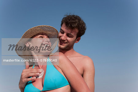 Man putting sunscreen on girlfriend