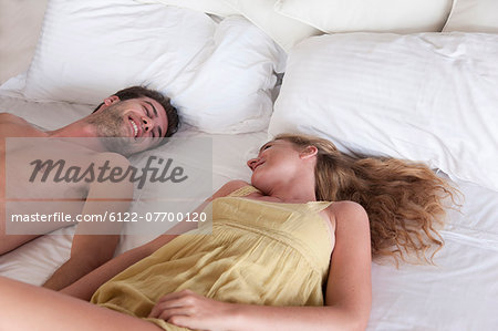 Smiling couple laying in bed together