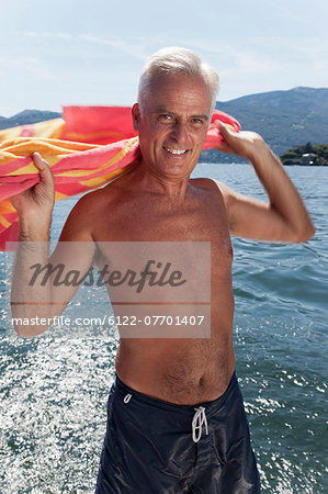 Older man drying off with towel on lake