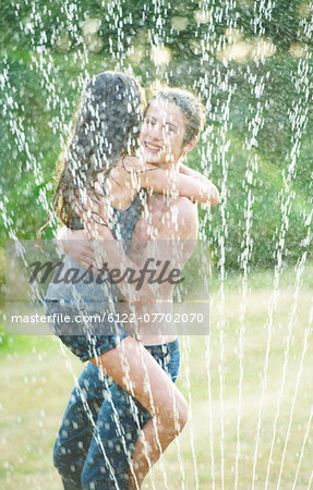 Friends hugging in sprinkler