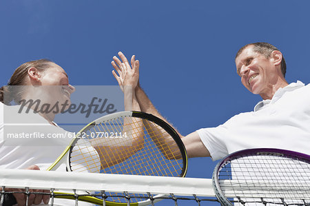 Older couple high fiving during tennis