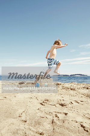 Boy stomping on sandcastle on beach