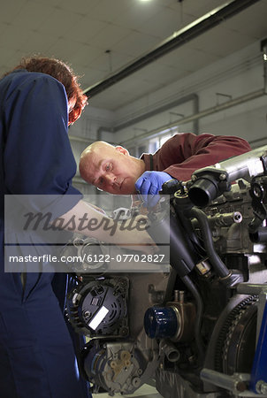 Teacher helping student with car engine