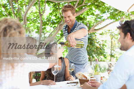 Man pouring wine for friends at table