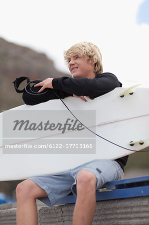 Teenage boy with surfboard on beach