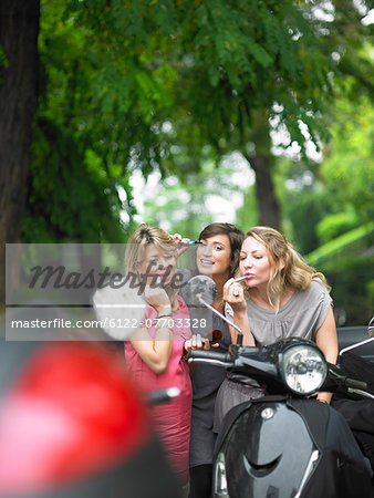 Women applying makeup in side mirror