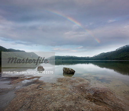 Rainbow stretching over rocky beach