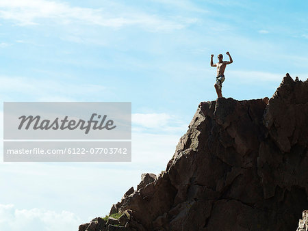 Man cheering on top of rocky hillside