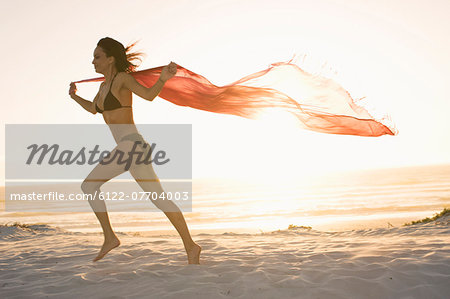 Woman running with sarong on beach