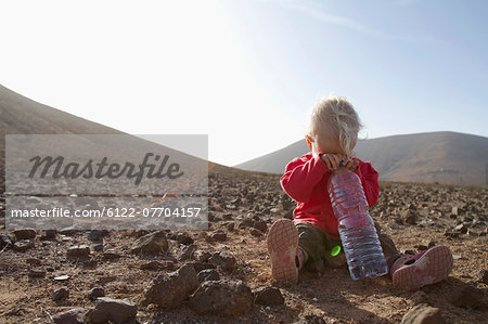 Toddler with bottle of water in desert