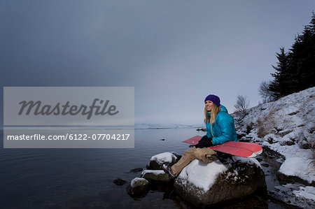 Snowboarder holding board by lake