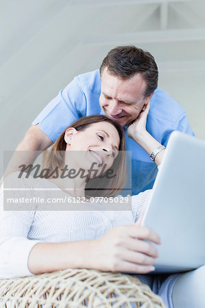 Couple using laptop in armchair