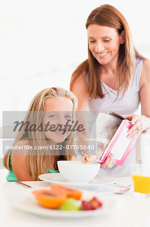 Mother pouring cereal for daughter