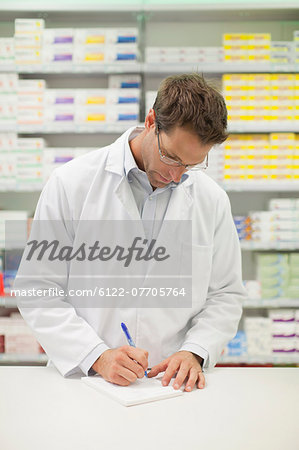 Pharmacist making notes at counter