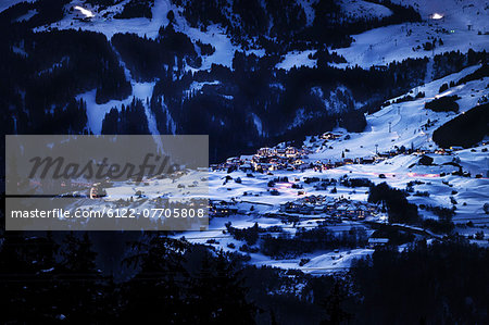 Lit village in snowy landscape at night