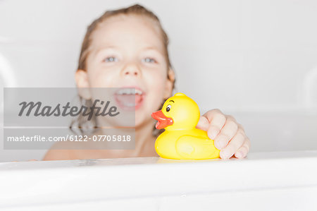 Girl playing with rubber duck in bath