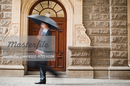 Businessman carrying umbrella on street