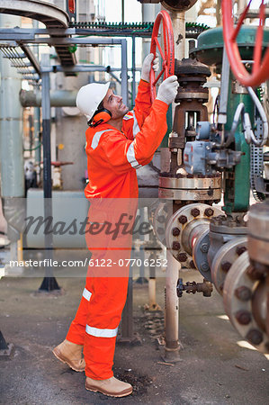 Worker adjusting gauge at oil refinery