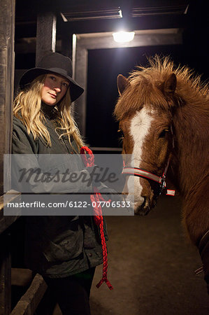 Woman smiling with horse in stable