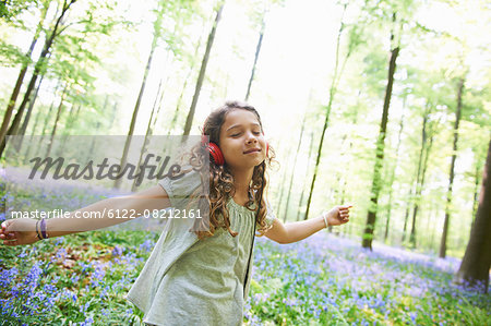 Girl listening to headphones in forest