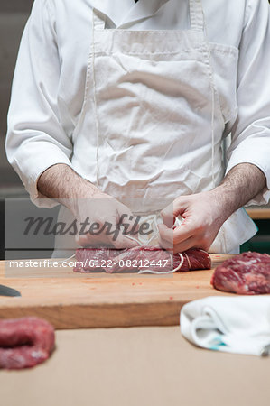 Butcher tying beef tenderloin with string